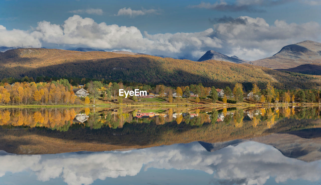 Beautiful scenic landscape with mountain and autumnal forest reflecting in water in norway.