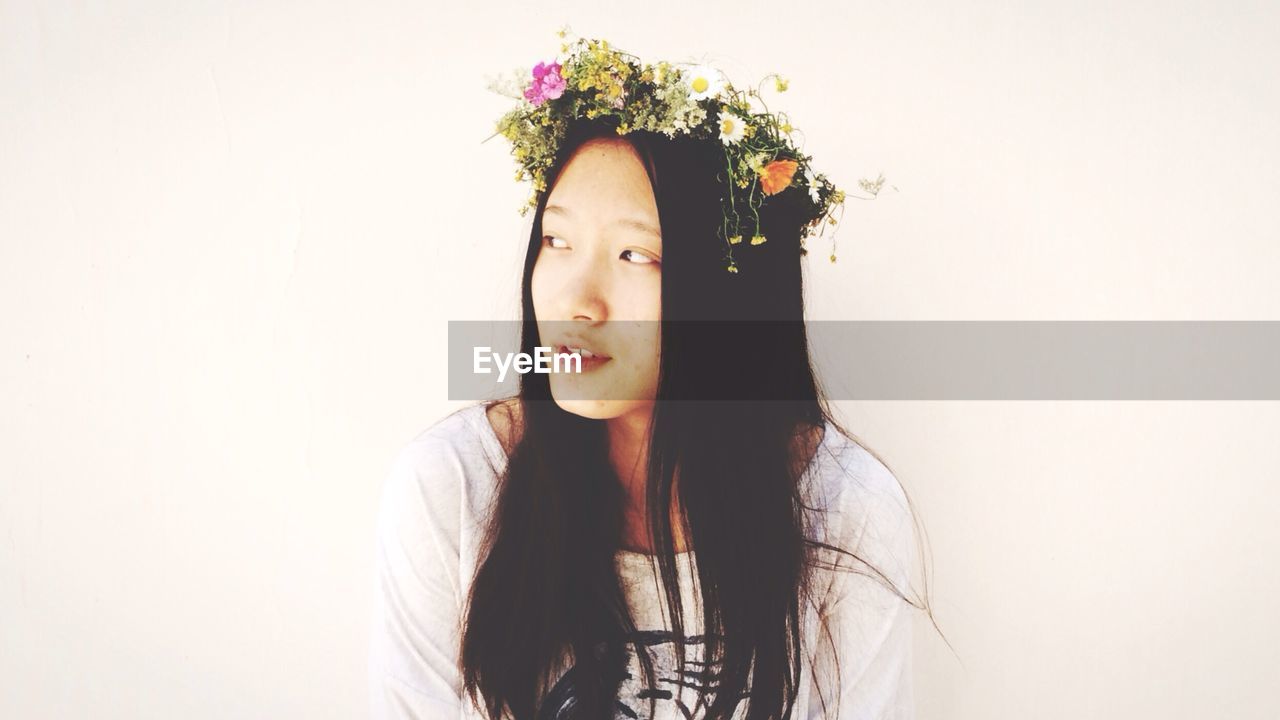 Young woman wearing flowers against white background