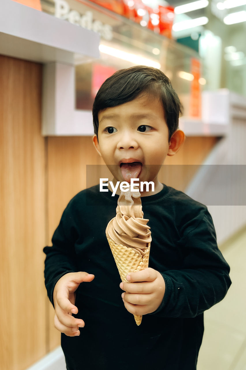 A boy is holding an ice cream and enjoying it