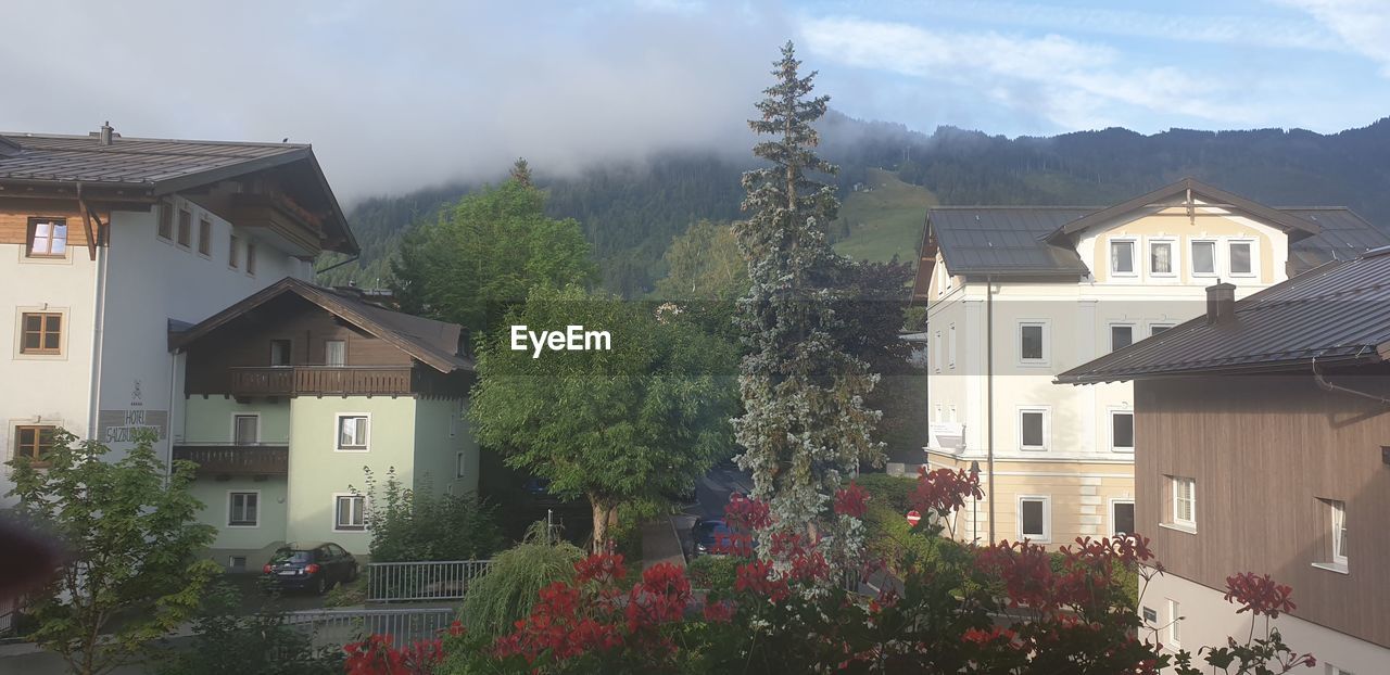 HOUSES BY BUILDINGS AGAINST SKY