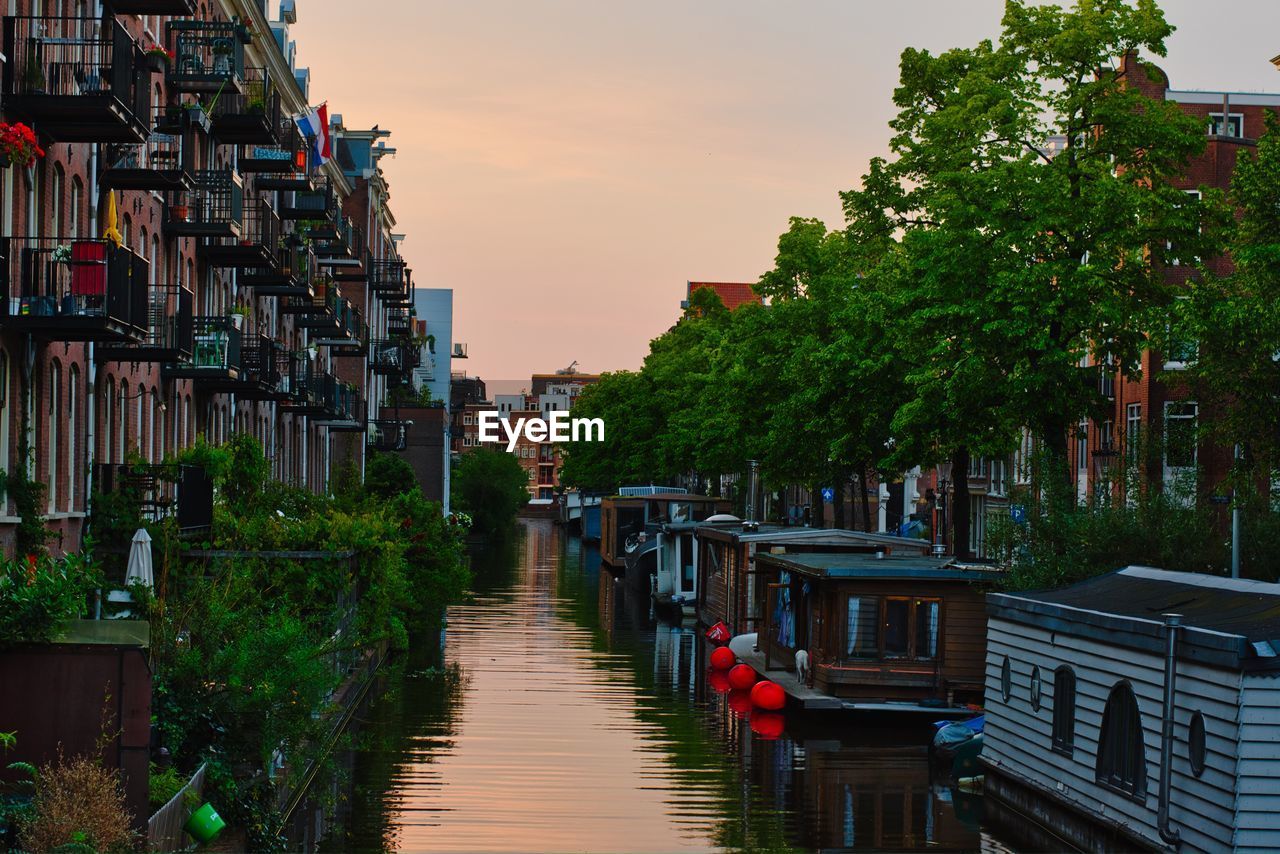 CANAL AMIDST BUILDINGS IN CITY AGAINST SKY