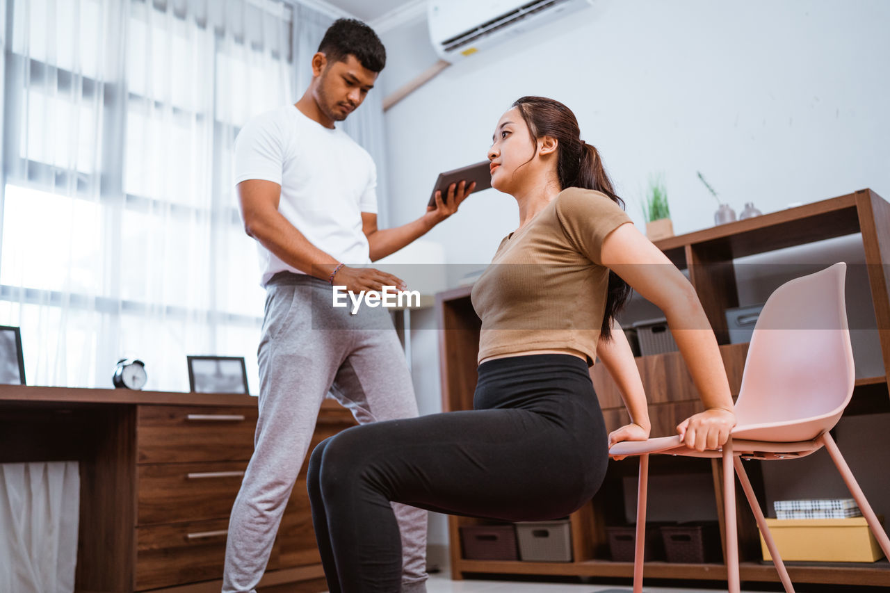 side view of female friends using mobile phone while sitting on exercise mat