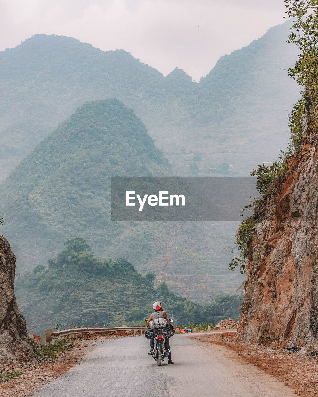 Rear view of man riding motorcycle on mountain road