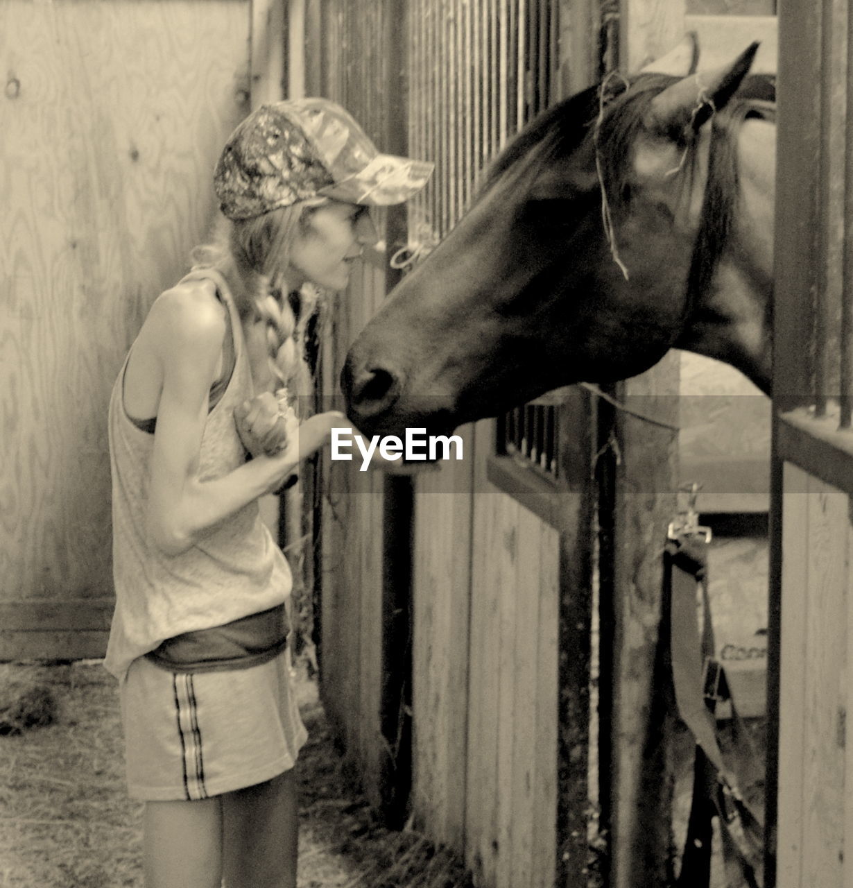 Young woman standing by horse in stable