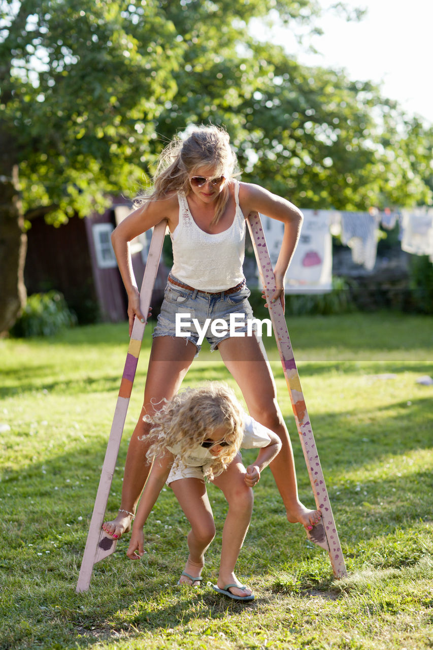 Sisters walking on stilts in garden