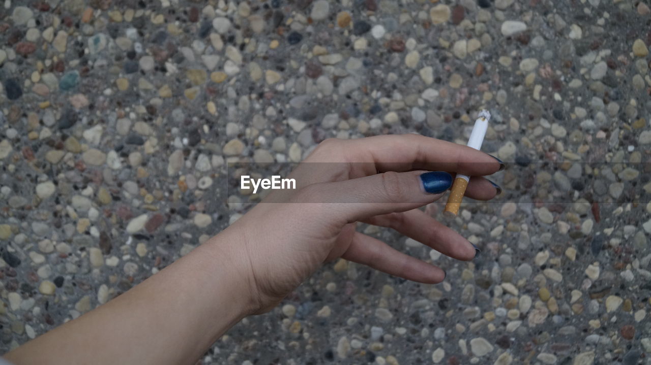 CLOSE-UP OF WOMAN HAND HOLDING PEBBLES ON BEACH