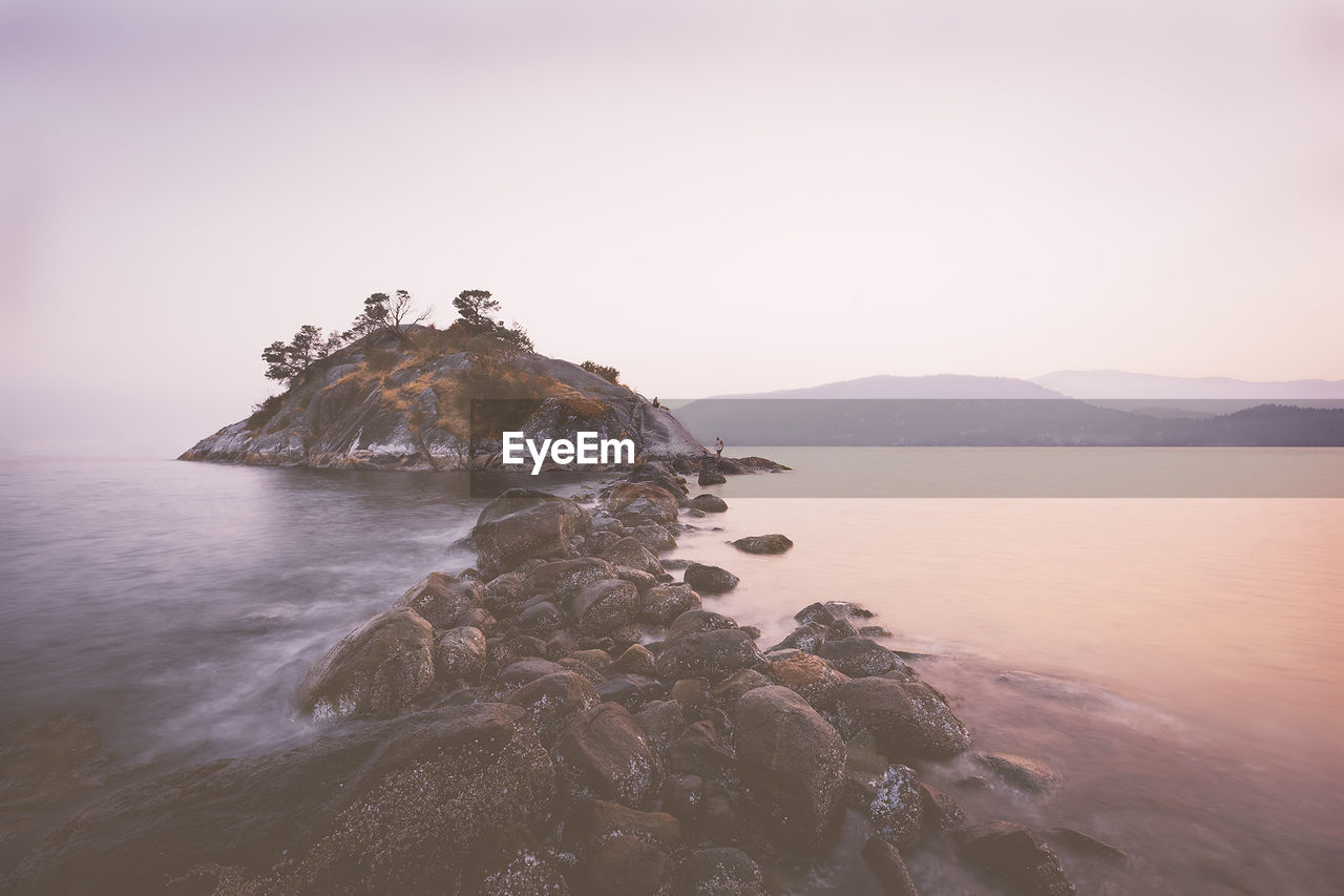 SCENIC VIEW OF SEA BY MOUNTAIN AGAINST CLEAR SKY