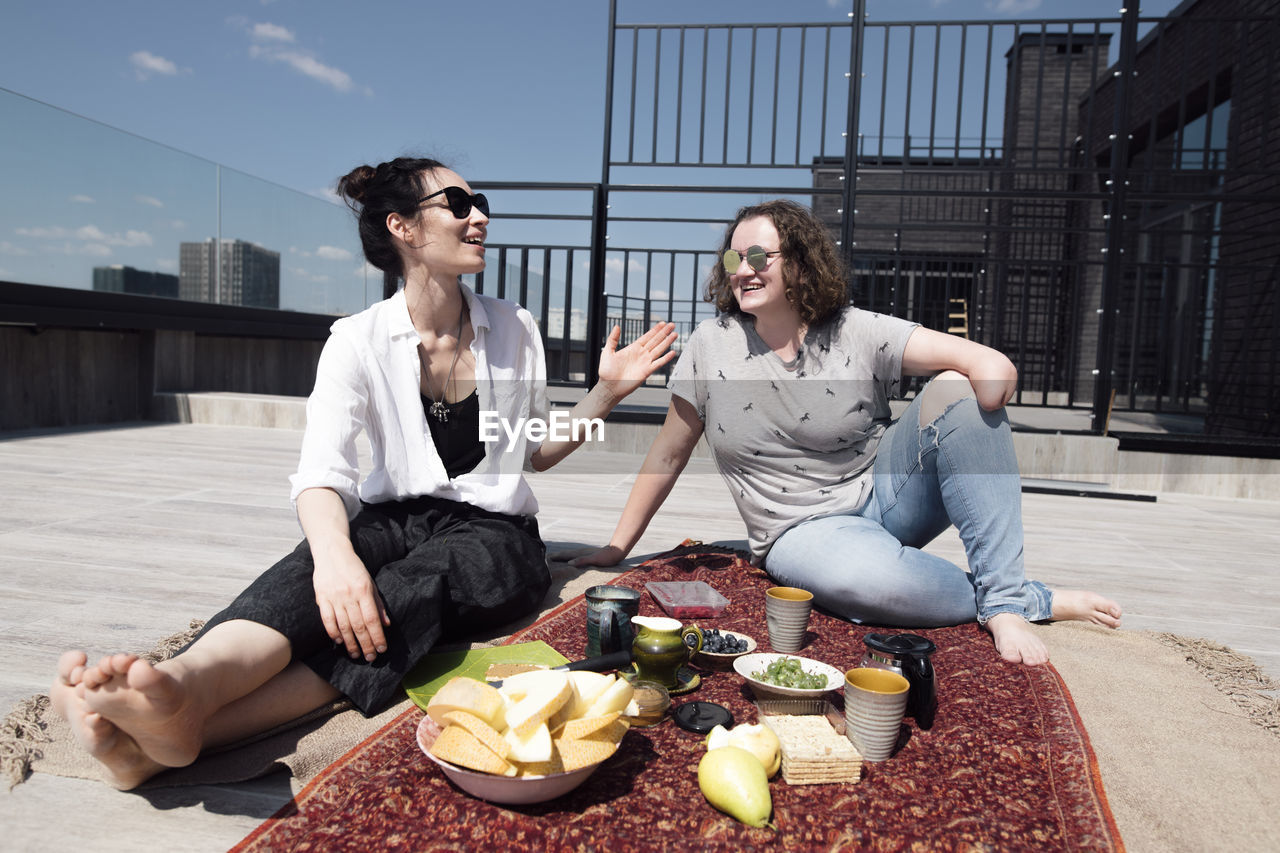Woman with below-elbow amputation with her friend having a healthy meal on the roof