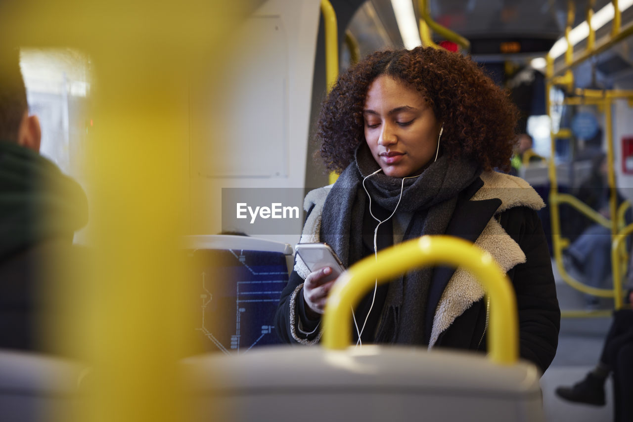 Young woman using cell phone in train