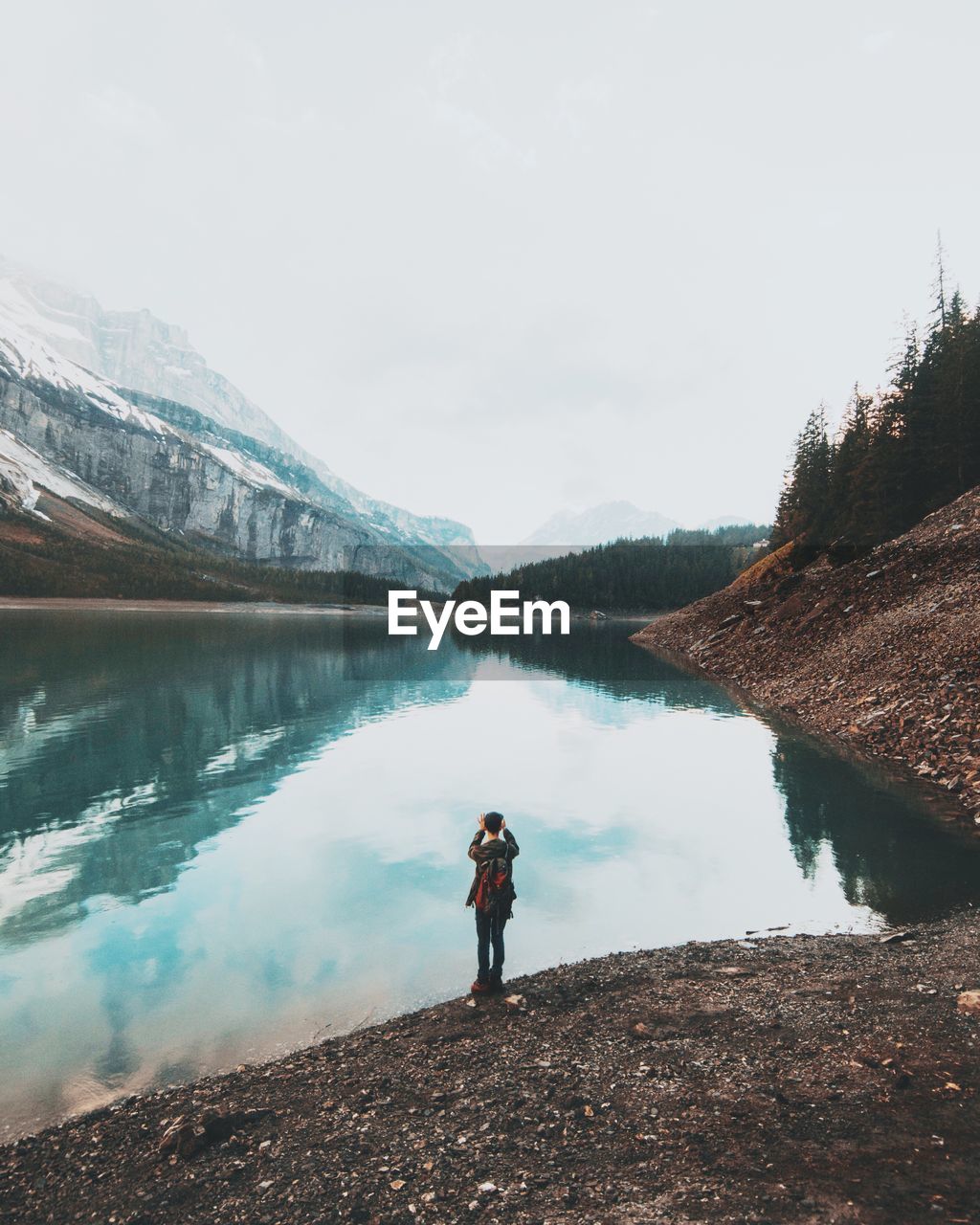 Rear view of man standing by oeschinen lake against clear sky