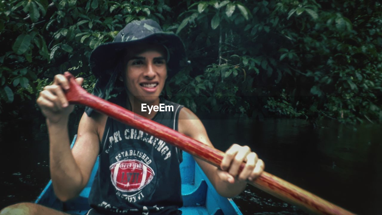 PORTRAIT OF SMILING YOUNG WOMAN HOLDING HAT IN WATER