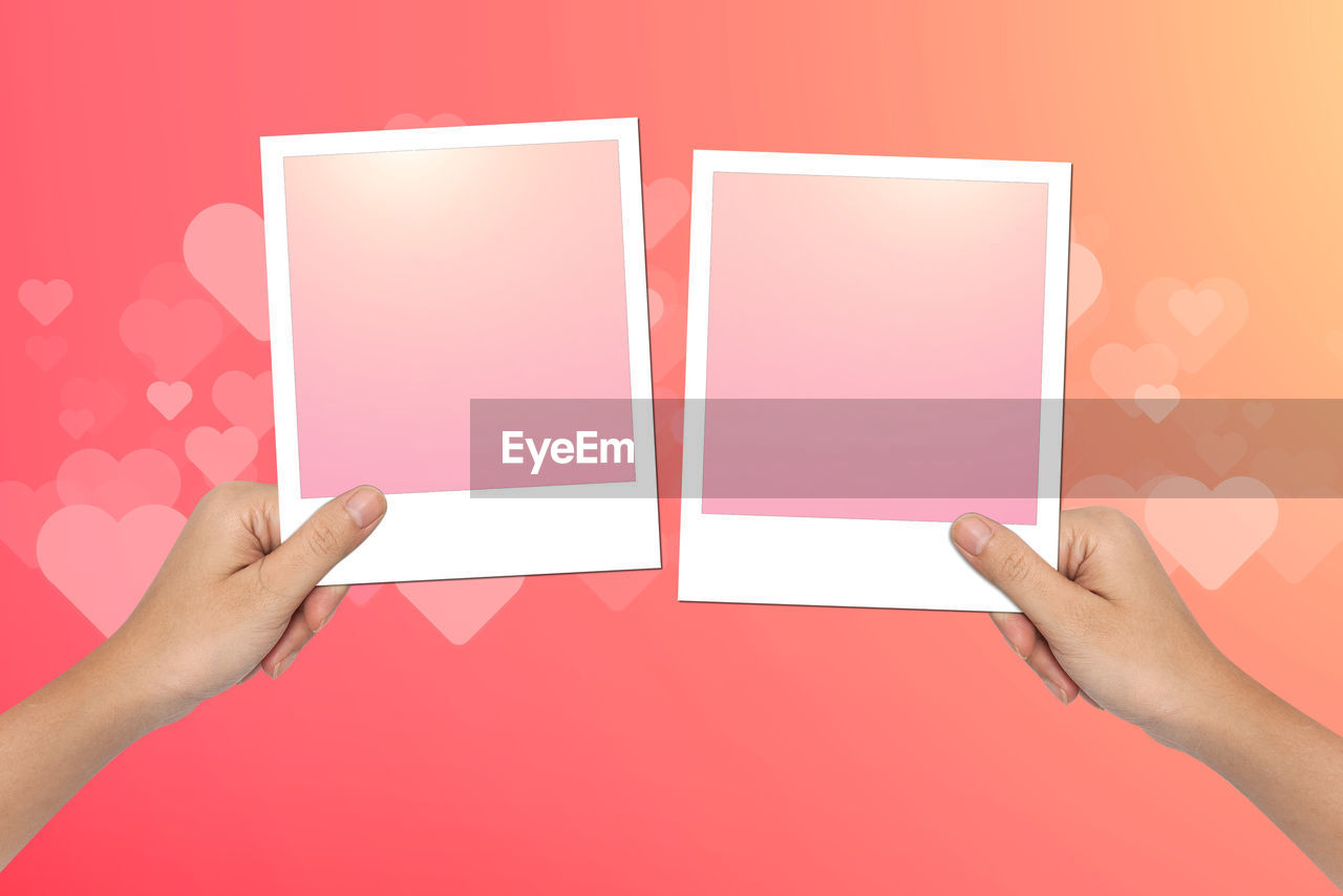 Close-up of hand holding instant print transfer against colored background