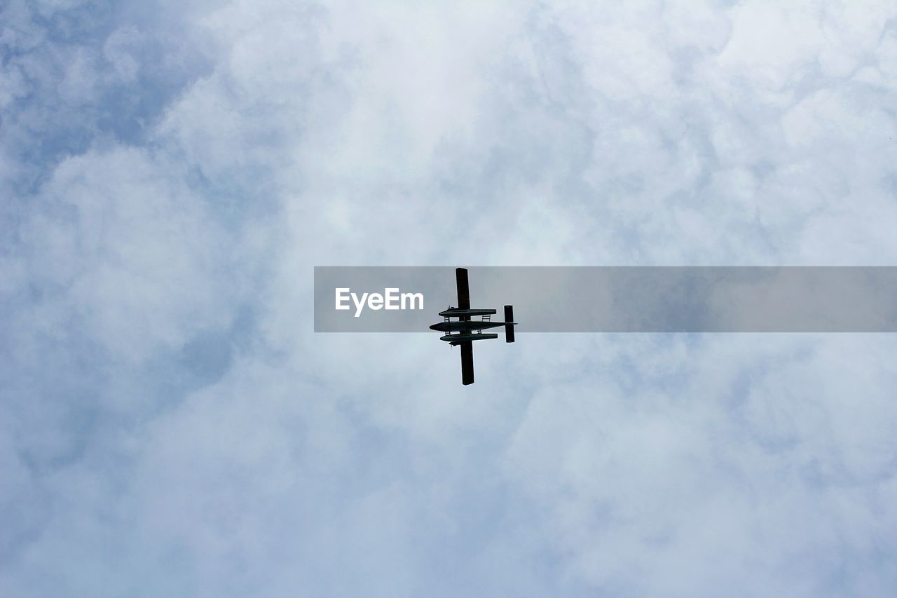 Low angle view of airplane flying against cloudy sky