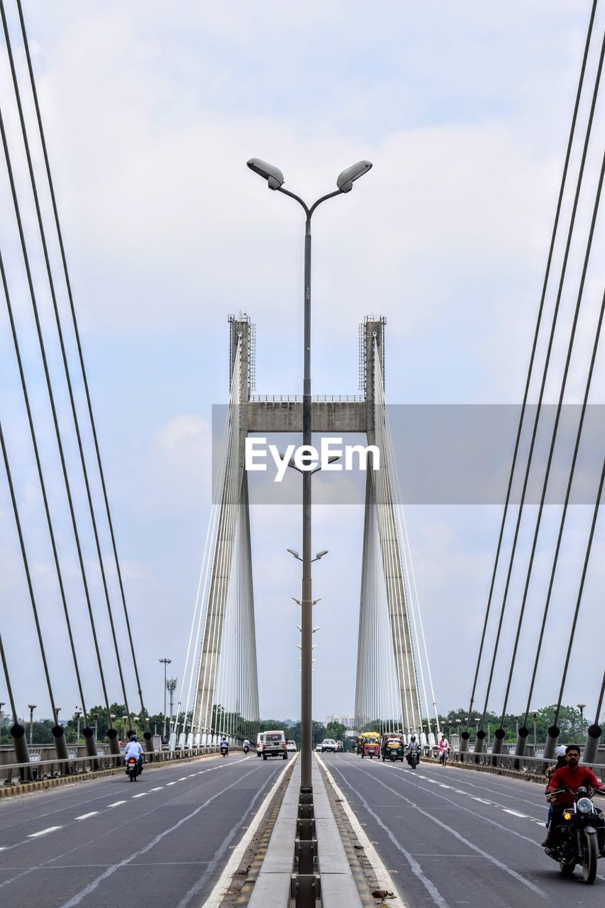 transportation, bridge, architecture, road, cable-stayed bridge, built structure, city, sky, car, motor vehicle, mode of transportation, street, travel destinations, highway, cloud, travel, nature, suspension bridge, sign, traffic, the way forward, overpass, freeway, engineering, lane, day, building exterior, cityscape, tourism, city life, symbol, land vehicle, street light, outdoors, vanishing point, motion, road marking, on the move, diminishing perspective, cable, marking, city street, line, landscape, water