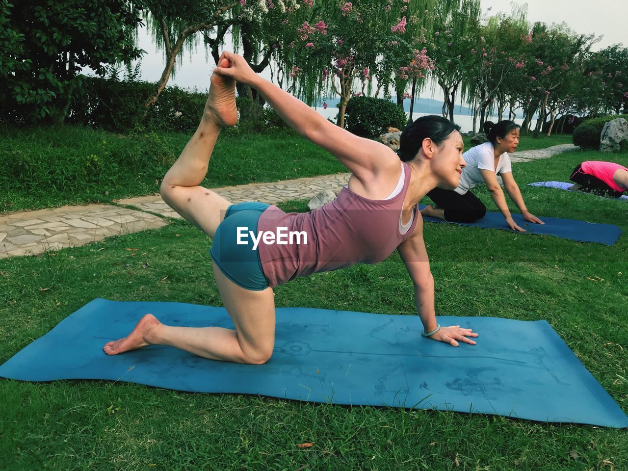 Women doing yoga on exercise mats at park