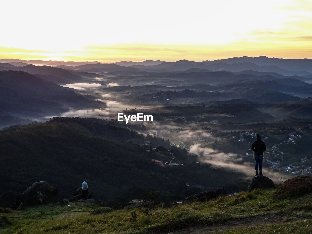 People standing on mountain against sky during sunset