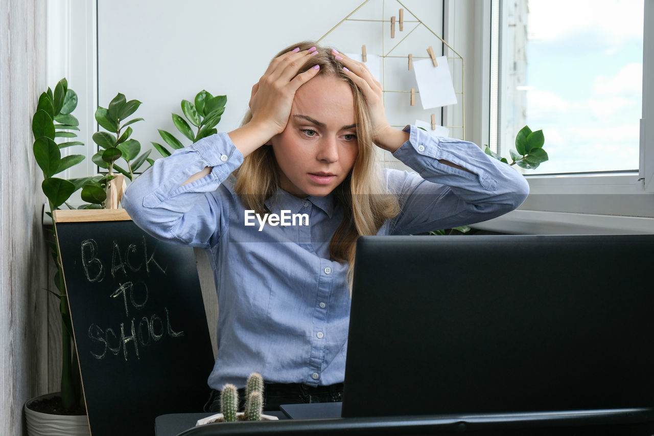 Tired sleepy young caucasian woman worker at desk workplace. overworking and sleeping deprivation. 