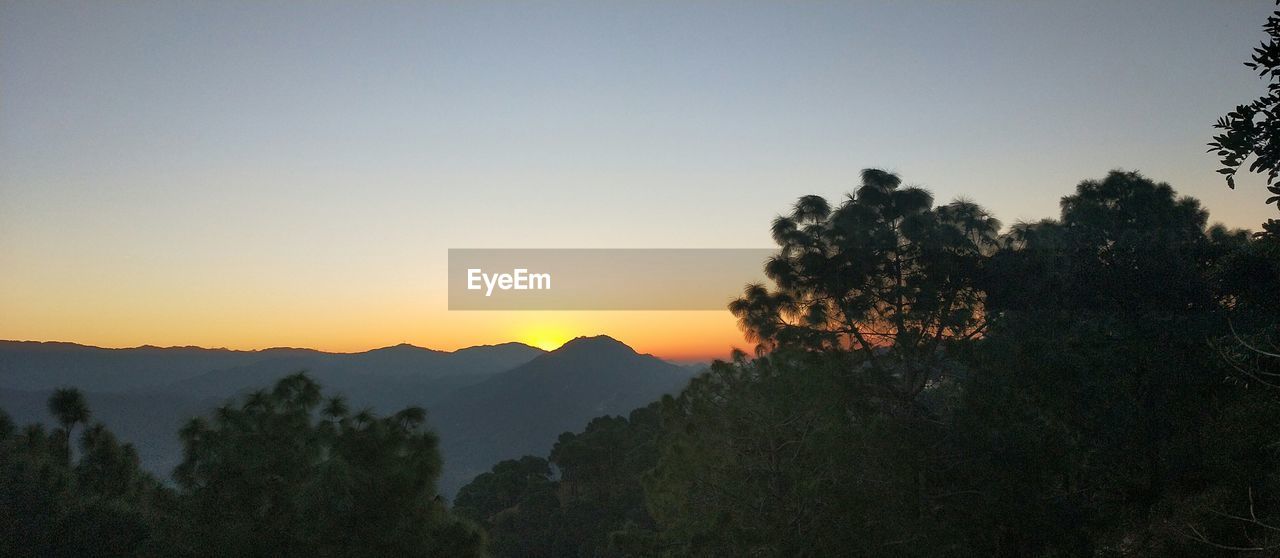 Scenic view of silhouette mountains against clear sky at sunset