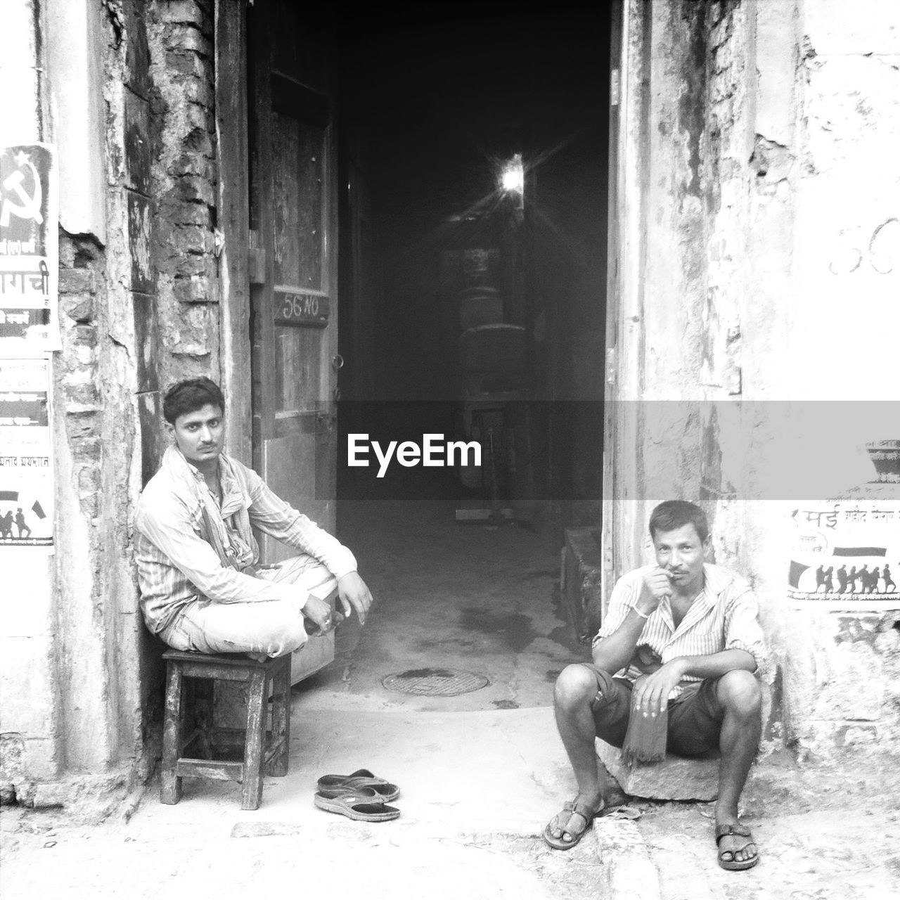 YOUNG WOMAN SITTING ON DOOR AT ENTRANCE