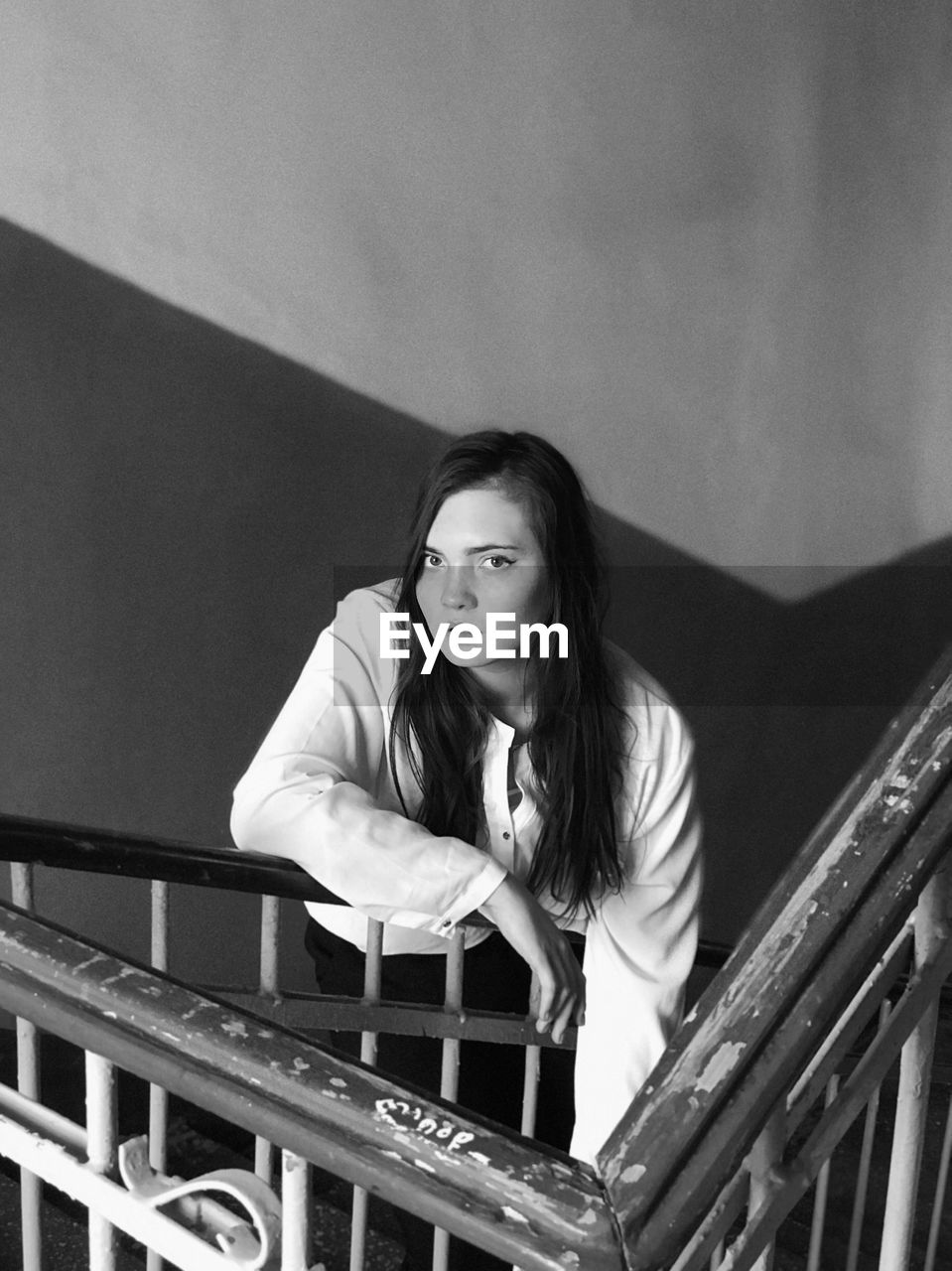 Portrait of woman standing against railing