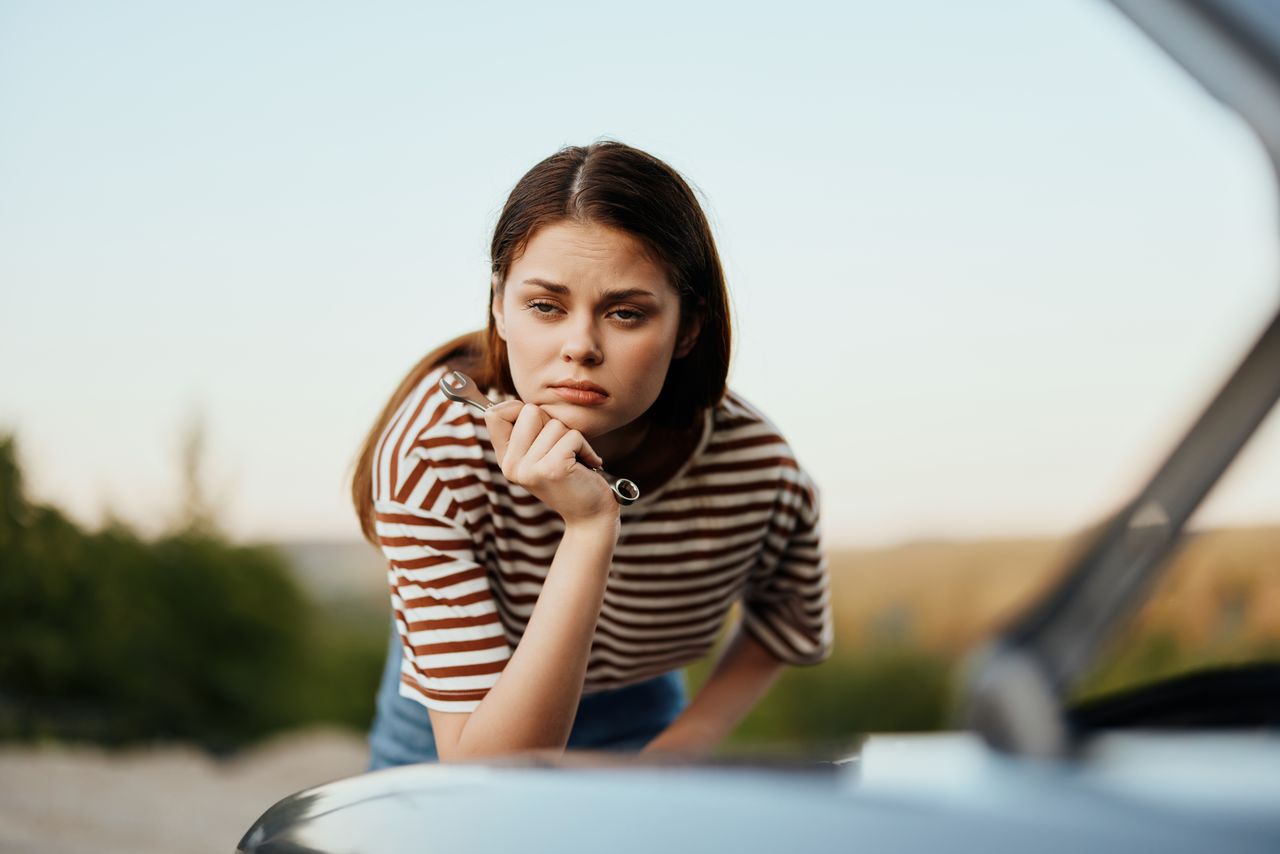 side view of young woman sitting on car