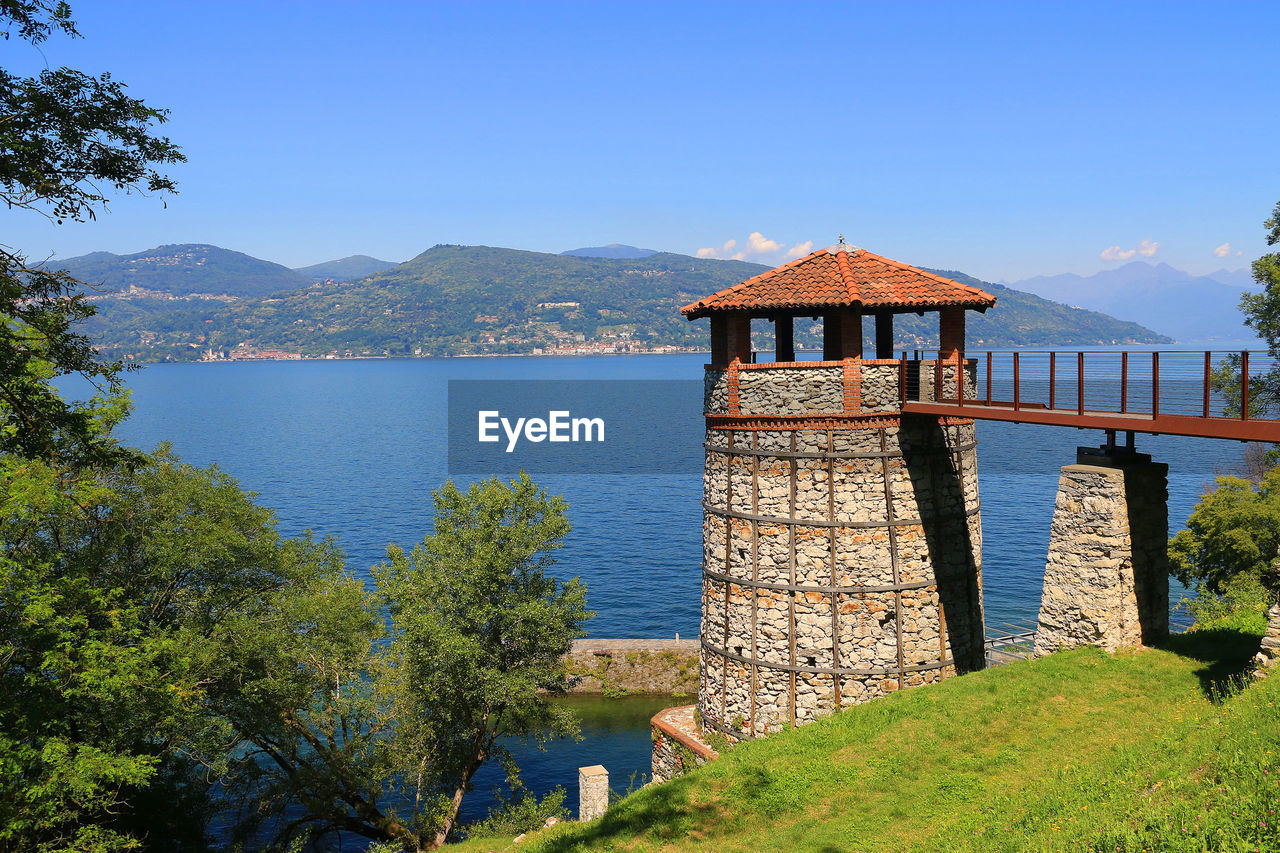 Built structure by lake against clear blue sky