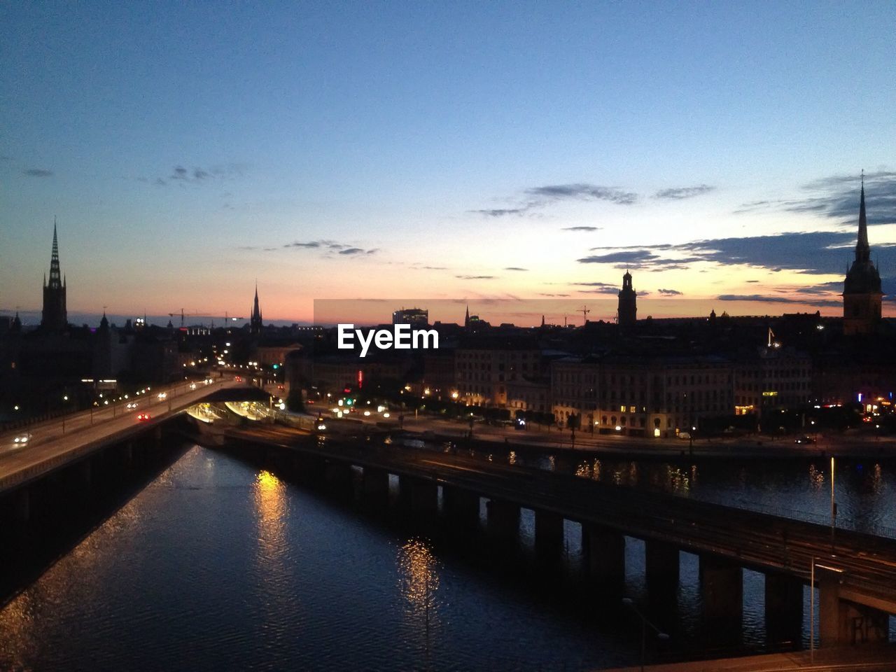 Bridges on river against sunset sky