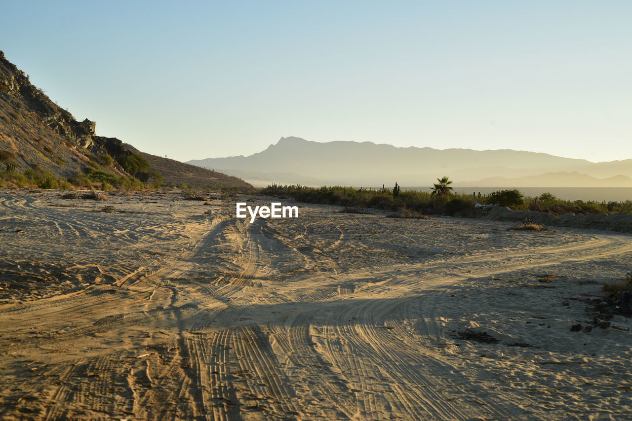 Scenic view of sandy beach and mountains against clear sky