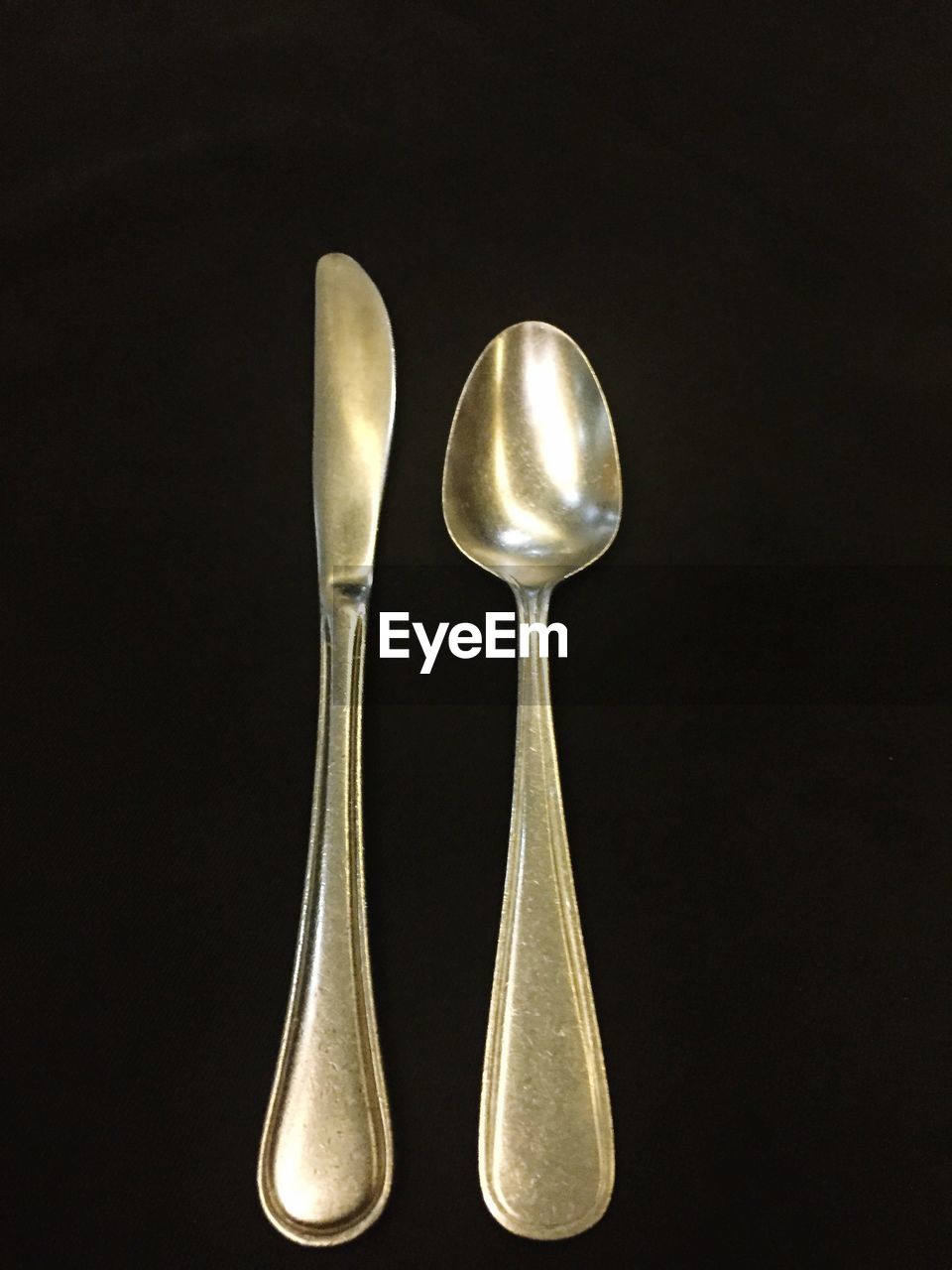 Close-up of table knife and spoon against black background