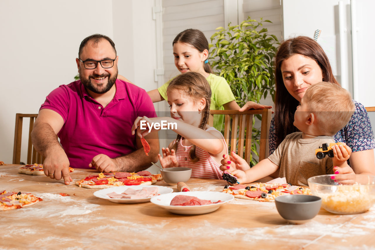 Cheerful family preparing pizza at home