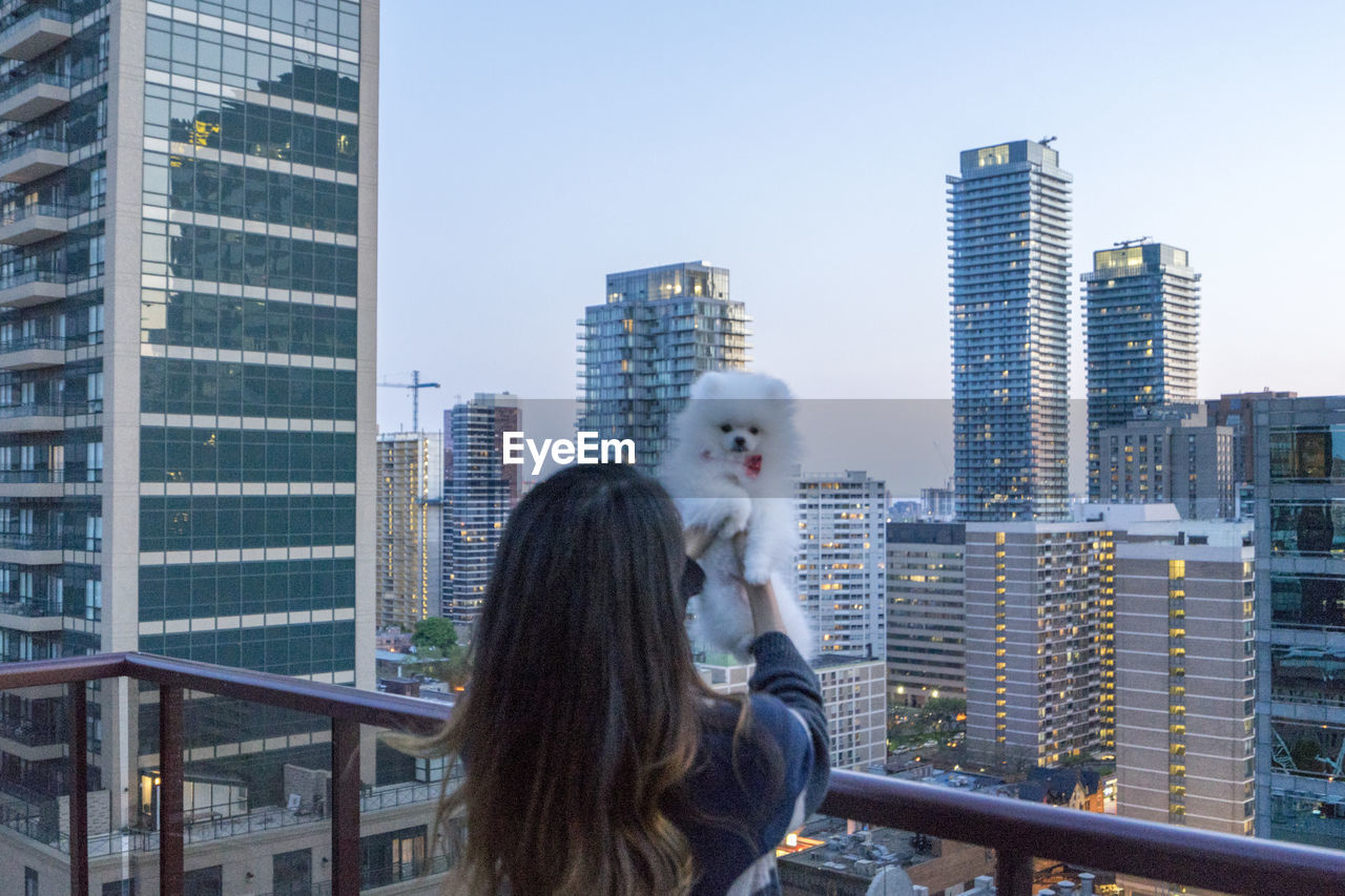 Rear view of girl holding pomeranian in balcony