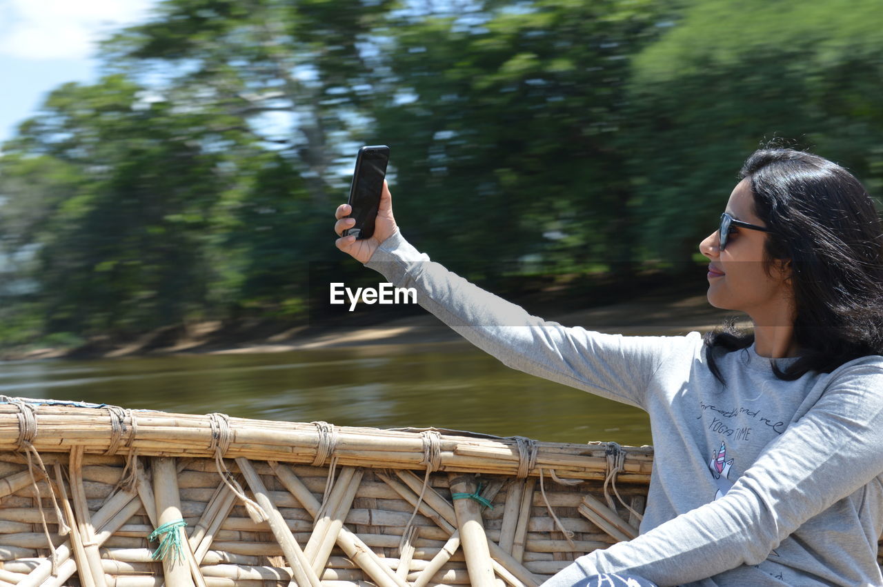 Young woman taking selfie while sitting in boat