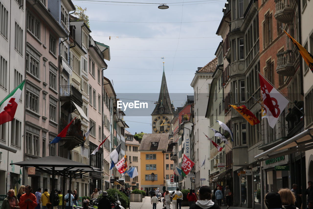 people walking on street amidst buildings in city