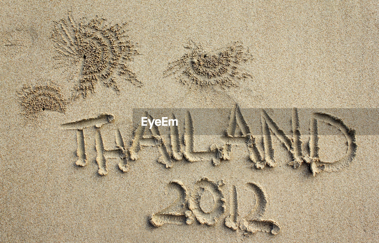 High angle view of thailand 2012 written on sandy beach