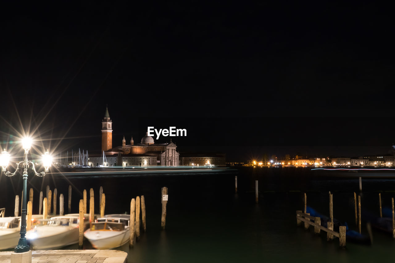 Grand canal by illuminated church of san giorgio maggiore against clear sky at night