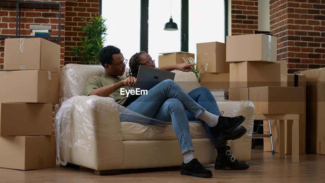 side view of woman using mobile phone while sitting on sofa at home