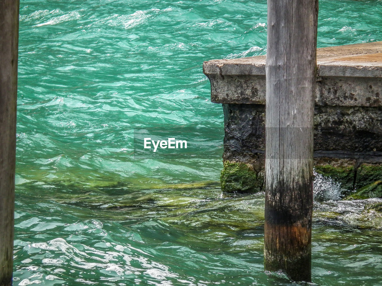 CLOSE-UP OF WOODEN POST IN WATER
