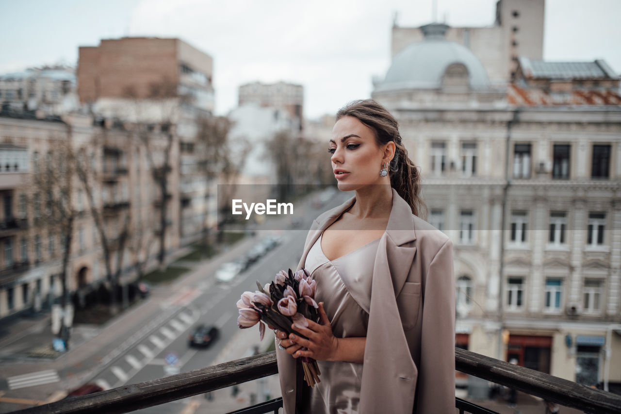 Woman standing by railing in city