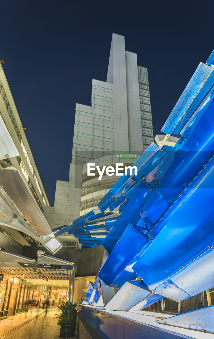 LOW ANGLE VIEW OF ILLUMINATED MODERN BUILDINGS AGAINST BLUE SKY