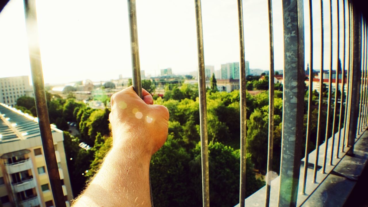Cropped image of man holding fence against sky