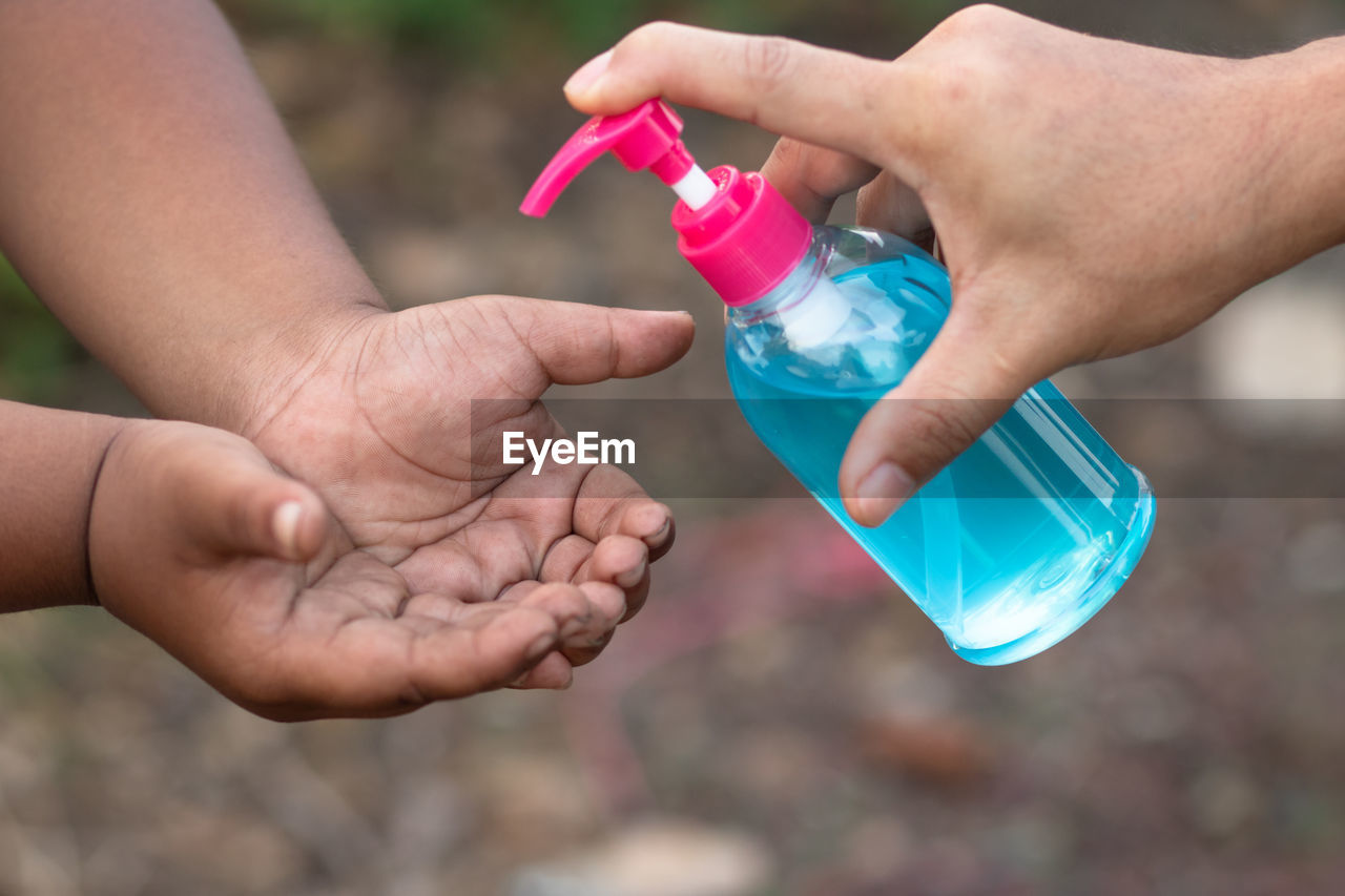 CROPPED IMAGE OF PERSON HOLDING BOTTLE WITH WATER