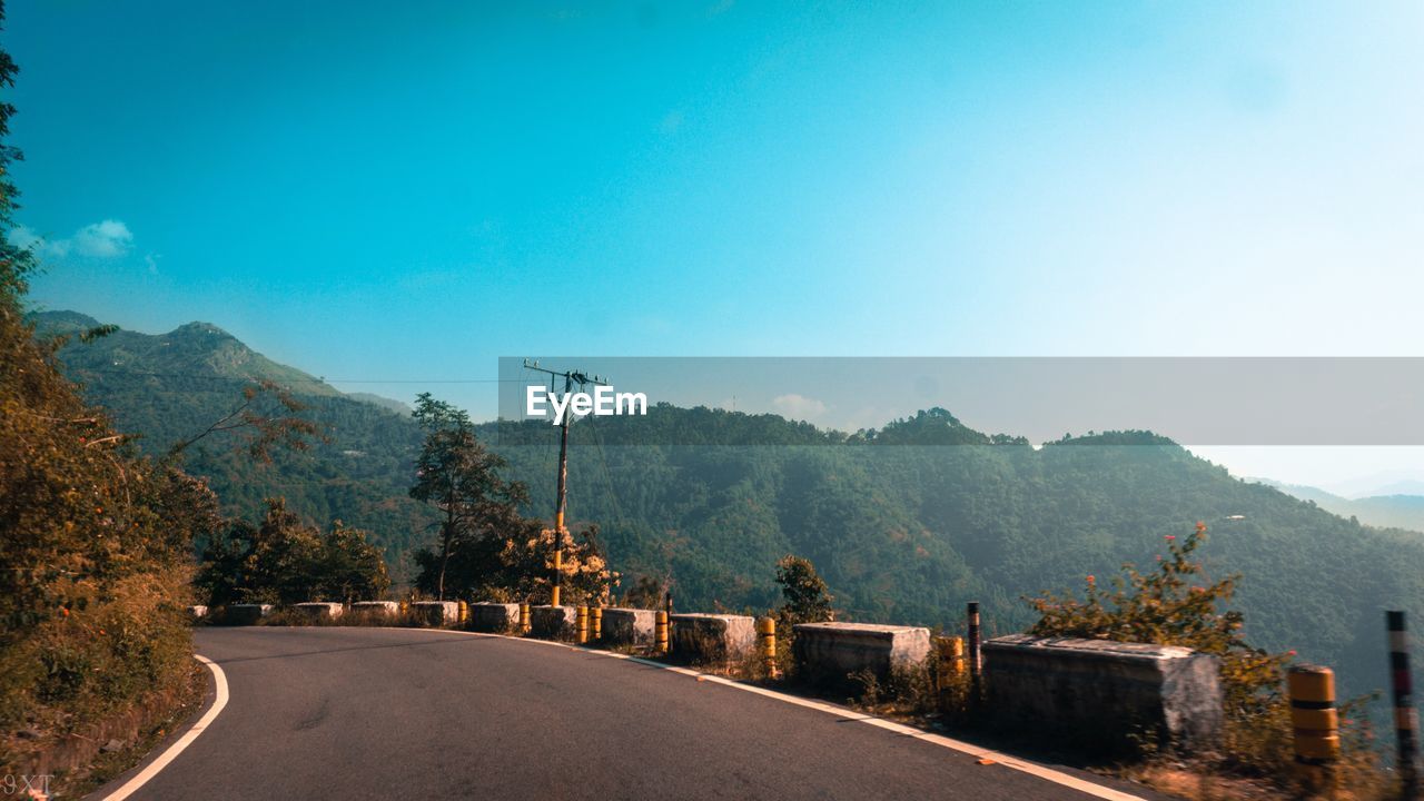 Road by mountains against clear blue sky