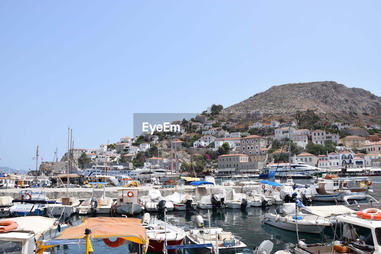 Sailboats moored at harbor against clear blue sky