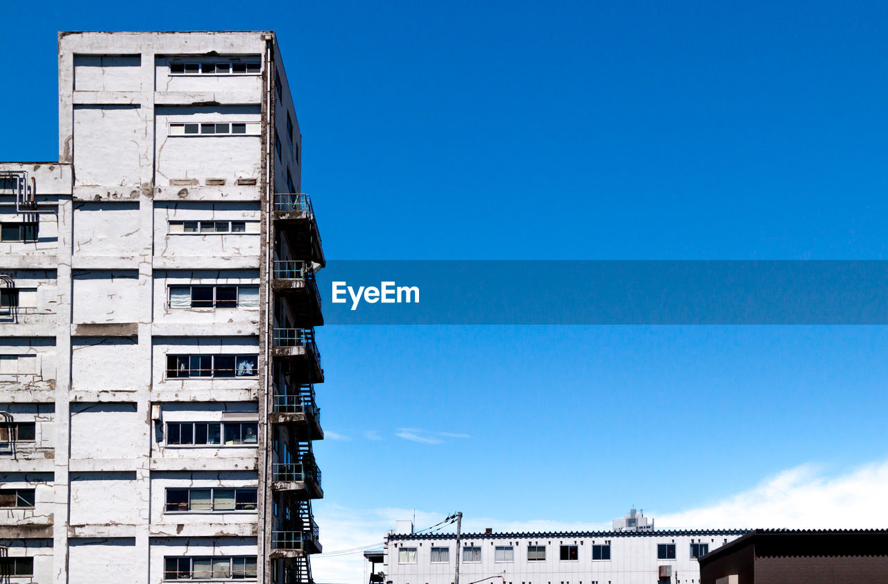 Low angle view of old factory buildings against clear blue sky