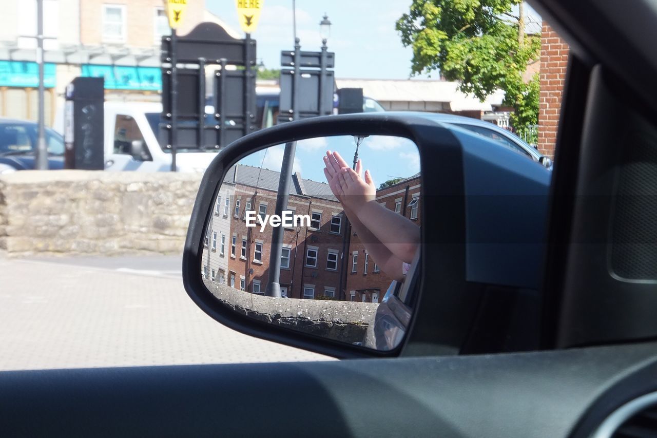 Reflection of hands on side-view mirror of car