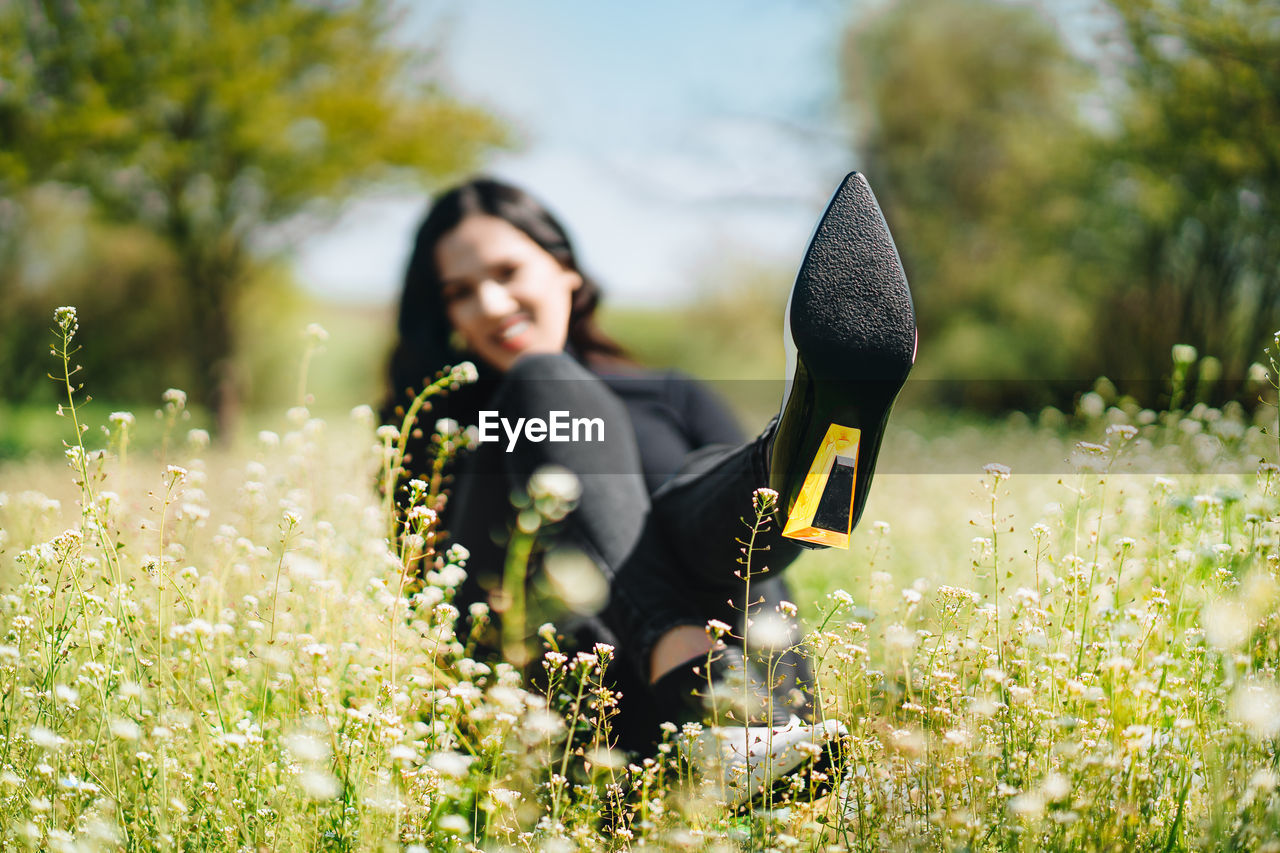 Woman with boots standing on field by flowering plants in summer