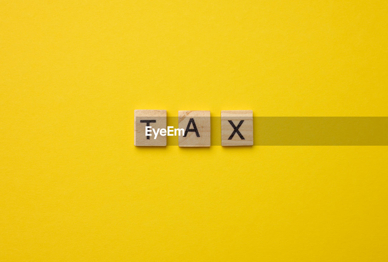 CLOSE-UP OF INFORMATION SIGN ON YELLOW WALL AGAINST ORANGE BACKGROUND