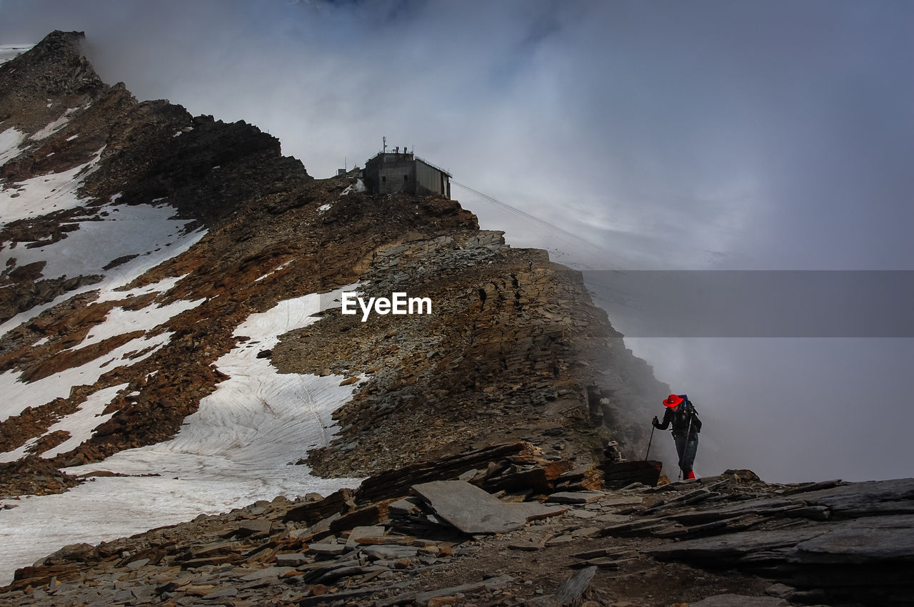 Hiker standing on mountain during foggy weather