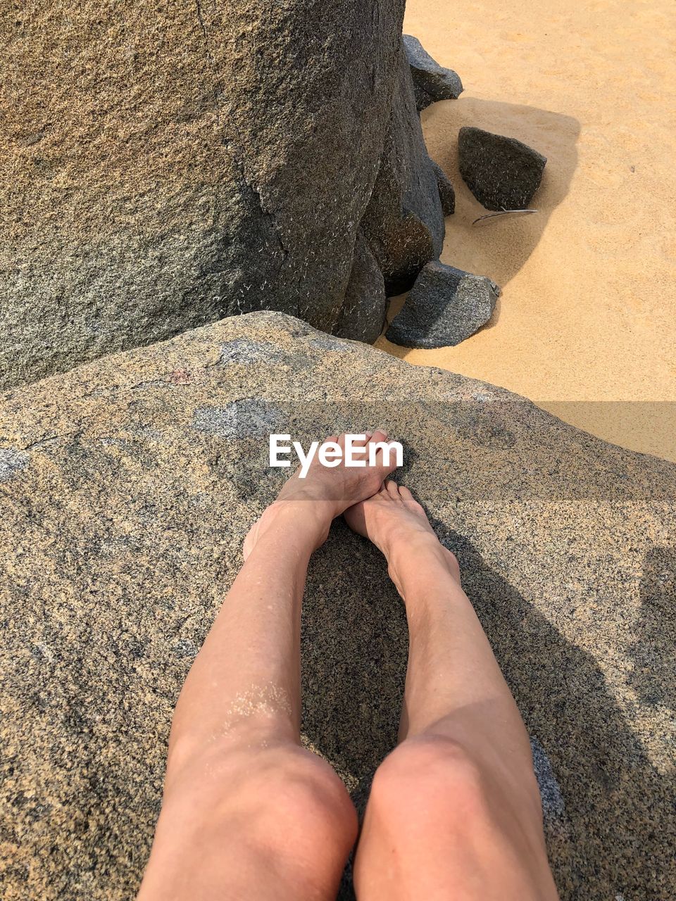 LOW SECTION OF MAN LEGS ON ROCK AT BEACH