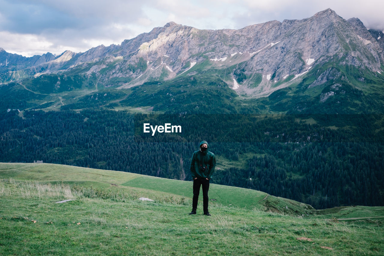 Rear view of man standing on mountain against sky